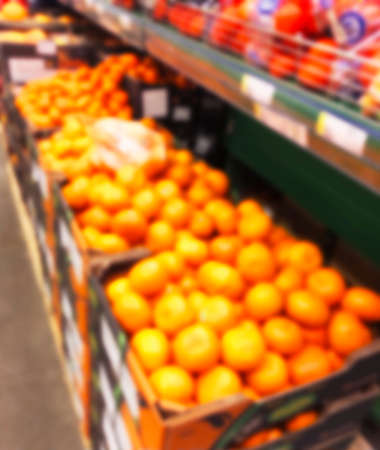 Blurred fresh fruits and vegetables at retail store. Abstract background of supermarket. Grocery market blurred background. Fruits in store racks. Interior shopping mall defocused backgroundの写真素材