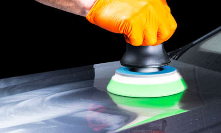Car polish wax worker hands applying protective tape before polishing. Buffing and polishing car....