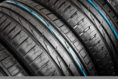 Studio shot of a set of summer car tire on black background. Tire stack background. Car tyre...