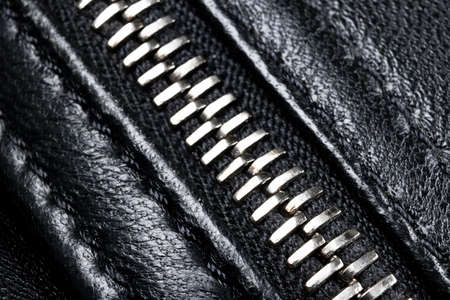 Macro shot of zipper on black leather texture background with stitching. Horizontal background from a close-up of black leather materialの写真素材