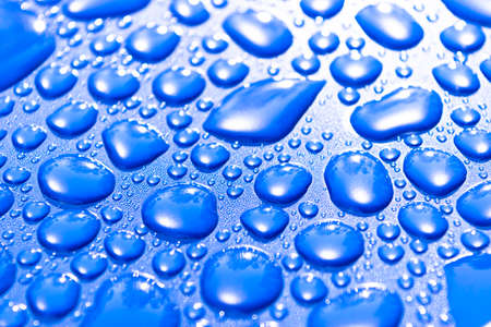 Transparent still water drops on light blue background. Blue water drops. Drops of rain on glass. Blue abstract water drop background. Water surfaceの写真素材
