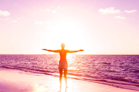 Girl silhouette looking beach sunset standing. Ocean sunset. Tropical beach. Travel concept. Girl looking at the sunset. Model girl silhouette over sunset sky. Swimming and splashing on summer beach over sunset.の写真素材