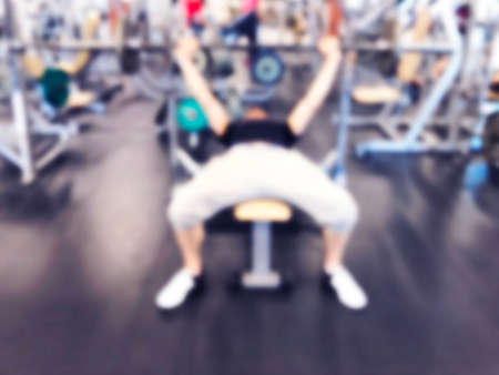 Blurred background with Man Lifting Barbell Row At Gym. Blur Fitness gym with people. Gym equipment concept. Blurred fitness gym Sport club center. Bokeh light backgroundの写真素材