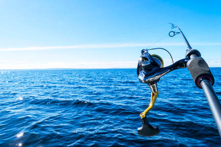 Fishing rod spinning with the line close-up. Fishing rod in rod holder in fishing boat due the fishery day. Fishing rod rings. Fishing tackle. Fishing spinning reel.の写真素材
