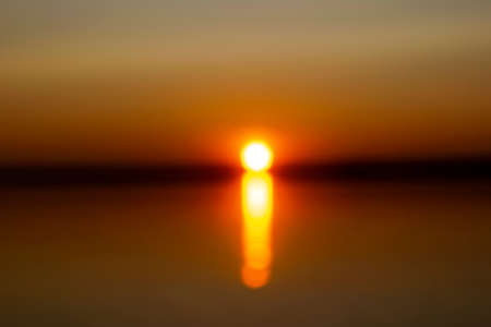 Abstract blurred background with summer lake landscape with golden sunrise. River landscape. Beautiful blur bokeh lights landscape with golden sunset.の写真素材