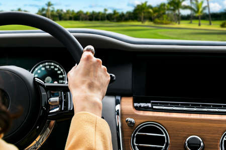 Woman's hands on the steering wheel driving modern luxury car. Concept woman driving. Hands holding...