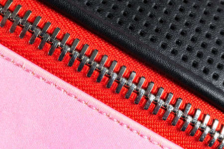 Macro shot of multicolored zipper on black leather texture background with stitching. Horizontal background from a close-up of black leather materialの写真素材