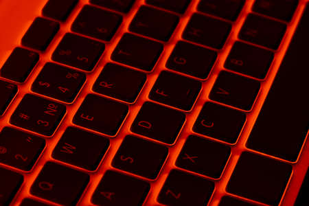 Close up view of a modern laptop computer keyboard keys. Soft lightning in red tones. Pc computer keyboard close upの写真素材