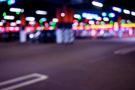 Blurred cars in car parking lot in shopping mall. Bokeh lights background. Abstract blur car parking lot for background. Blurred cars parking and bokeh lightの写真素材