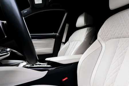 Modern luxury car white leather interior with natural wood panel. Part of leather car seat details with stitching. Interior of prestige modern car. White perforated leather. Car detailing. Car insideの写真素材