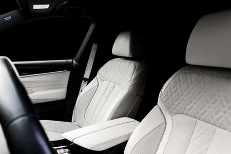 Modern luxury car white leather interior with natural wood panel. Part of leather car seat details...
