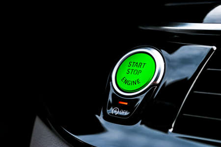 Car dashboard with focus on green engine start stop button. Modern car interior details. start/stop button. Car inside. Ignition remote starterの写真素材