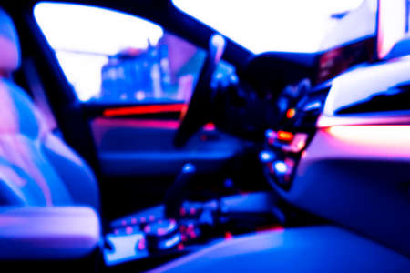 Blurred image of car interior. Dashboard. Blur defocused transportation background. Driving inside car. Bokeh light background. Blurred speedometer and tachometerの写真素材