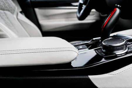 Modern luxury car white leather interior with natural wood panel. Part of leather car seat details with stitching. Interior with dashboard. White perforated leather. Car detailing. Car insideの写真素材