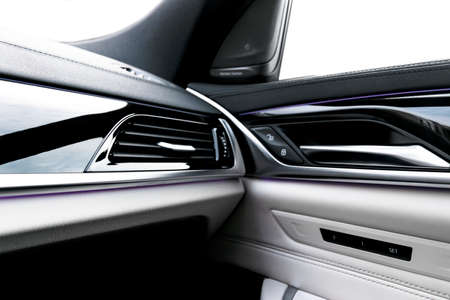 Door handle with power window control buttons of a luxury passenger car. White perforated leather...