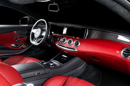 Red luxury modern car Interior with steering wheel, shift lever and dashboard. Clipping path. Detail of modern car interior. Automatic gear stick. Part of leather seats with stitching in expensive carの写真素材