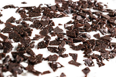 Grated chocolate. Pile of ground chocolate isolated on white background. Crushed dark chocolate...