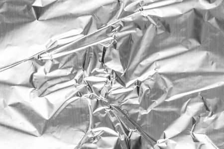 Close up of aluminium foil crumpled. Silver aluminium foil texture background. Abstract metallic paper pattern. Texture of crumpled aluminum kitchen foil. Silver abstract backgroundの写真素材