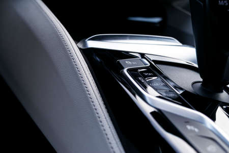 Track control buttons near automatic gear stick in a white leather interior of a modern car. Car...