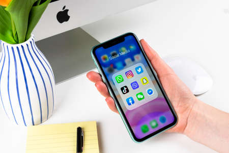 Helsinki, Finland, January 28, 2020: Apple iPhone 11 in woman hands with icons of social media...