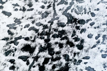 Aerial view of a frozen lake surface. Aerial Snow pattern on the frozen lake. Frozen lake ice captured with a drone. Aerial photography. Winter snow textureの写真素材