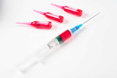 Syringe close up with ampoules on white medical table. Vaccine in plastic hypodermic syringe....