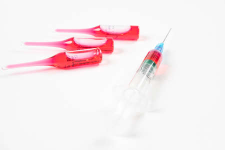 Syringe close up with ampoules on white medical table. Vaccine in plastic hypodermic syringe. Close-up of medical syringe. Syringe with an injection and vaccination solution.の写真素材