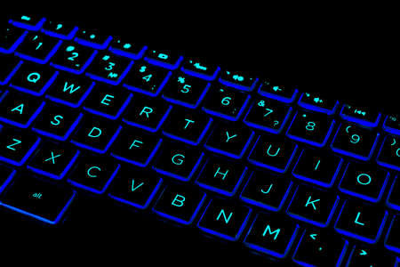 Close up view of a modern laptop computer keyboard keys. Soft lightning in green tones. Pc computer...