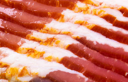 Macro shot several rows of sliced smoked bacon isolated on white background. Fresh sliced bacon isolated over white background. Raw dry-cured  bacon close up.の写真素材