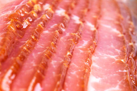 Macro shot several rows of sliced smoked bacon isolated on white background. Fresh sliced bacon isolated over white background. Raw dry-cured  bacon close up.の写真素材