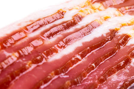 Macro shot several rows of sliced smoked bacon isolated on white background. Fresh sliced bacon isolated over white background. Raw dry-cured  bacon close up.の写真素材