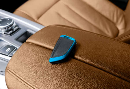 Closeup inside vehicle of wireless key ignition. Start engine key. Car key remote in brown...
