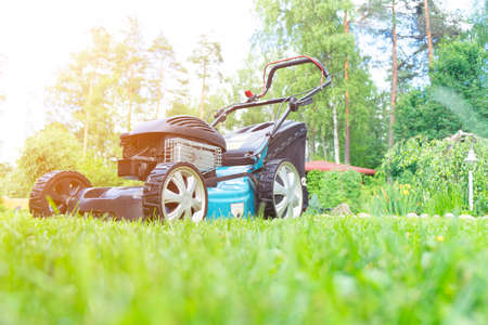 Mowing lawns. Lawn mower on green grass. Mower grass equipment. Mowing gardener care work tool close...