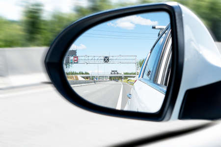 Cars drive along a high road with motion blur background. Car side mirror with traffic. Car rear...