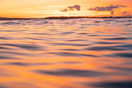 Water surface. View of a Sunset sky background. Dramatic gold sunset sky with evening sky clouds over the sea. View of a Crystal clear sea water texture. Landscape. Small waves. Water reflectionの写真素材