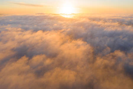 Aerial view gold sunrise over clouds in blue sky. Aerial top view cloudscape. Texture of clouds....