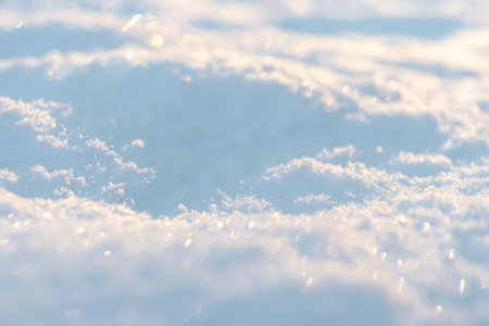 Macro shot background of fresh white snow at the sunset. Snowflakes texture. Snow texture winter background. Shiny snow with bokeh sun rays.の写真素材