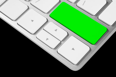 Close up view of a computer notebook keyboard with one green empty button isolated on blacke background. Technology background empty space for textの写真素材