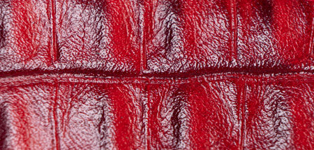 Red perforated leather texture background. Red leather close up. Macro shot of shiny leather...