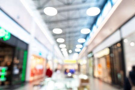 Abstract blurred background of modern luxury department store hall or shopping center mall. Blurred lights background. Blurred defocused bokeh lights with modern white interior architectureの写真素材