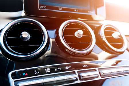 AC ventilation deck in luxury modern car Interior. Modern car black leather interior. Natural wood panel. Perforated black leather. Car interior. Car inside with sun raysの写真素材