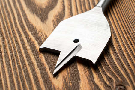 Feather wood drill bit on wooden background. Drill bit for wood on natural wood background. Spade drill. Carpenters tools background.の写真素材
