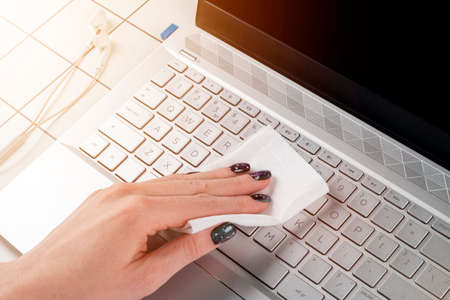 Woman cleaning computer keyboard. Female hands disinfecting laptop keyboard with antivirus wet wipes. Cleaning and disinfecting laptop computer with wet wipesの写真素材