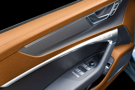 Car door handle inside the luxury modern car with brown leather texture with stitching. Switch...