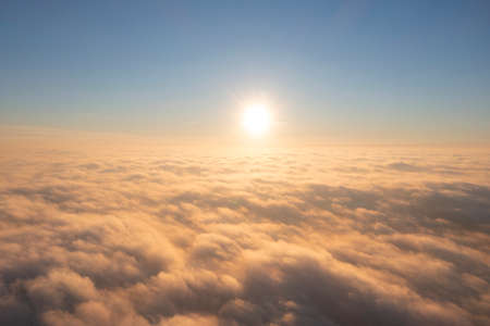 Aerial view gold sunrise over clouds in blue sky. Aerial top view cloudscape. Texture of clouds. View from above. Orange sunrise or sunset over clouds. Panorama clouds textureの写真素材