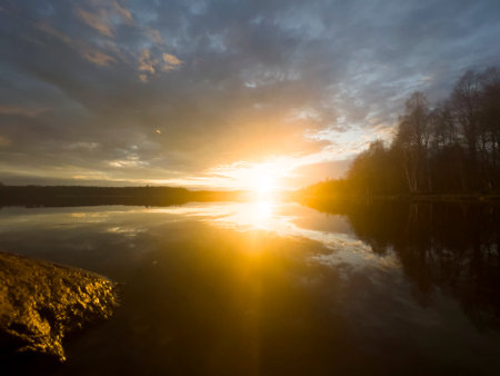 Water surface. View of a Sunset sky background. Dramatic gold sunset sky with evening sky clouds over the lake. Clear water texture. Landscape. Water reflectionの写真素材