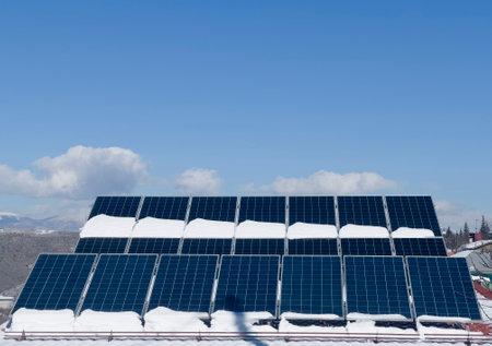 Blue Solar panel over blue sky, sun and clouds. Solar cell panels covered vith snow pattern for...