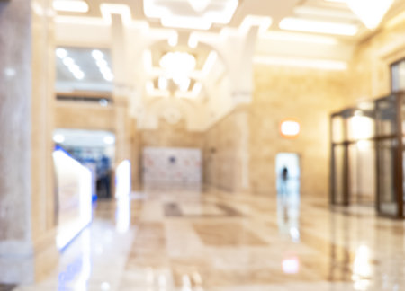 Abstract blurred background of modern luxury department store hall or shopping center mall. Blurred lights background. Blurred defocused bokeh lights with modern white interior architectureの写真素材