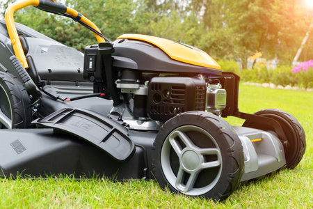 Mowing lawns. Lawn mower on green grass. Mower grass equipment. Mowing gardener care work tool close up view. Soft lightingの写真素材