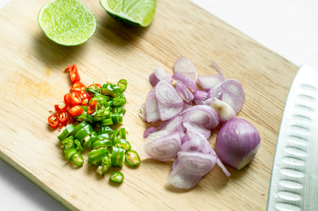 Red onion chopped, chilli chopped  and lemon on wooden chopping boardの写真素材
